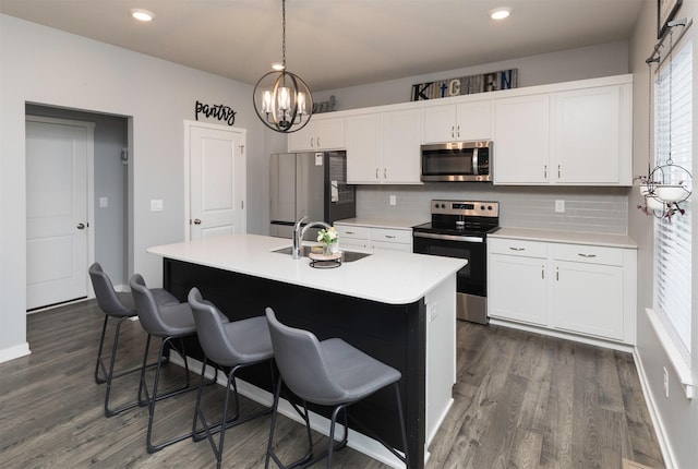 kitchen with an island with sink, appliances with stainless steel finishes, sink, and backsplash