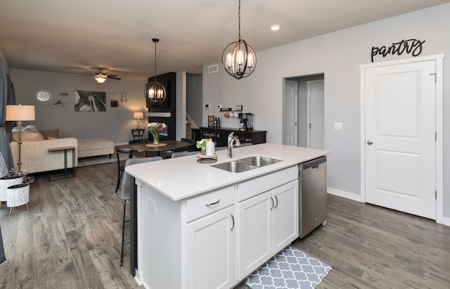 kitchen featuring pendant lighting, white cabinetry, sink, stainless steel dishwasher, and a center island with sink