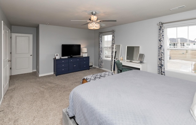 bedroom featuring ceiling fan, light colored carpet, and multiple windows