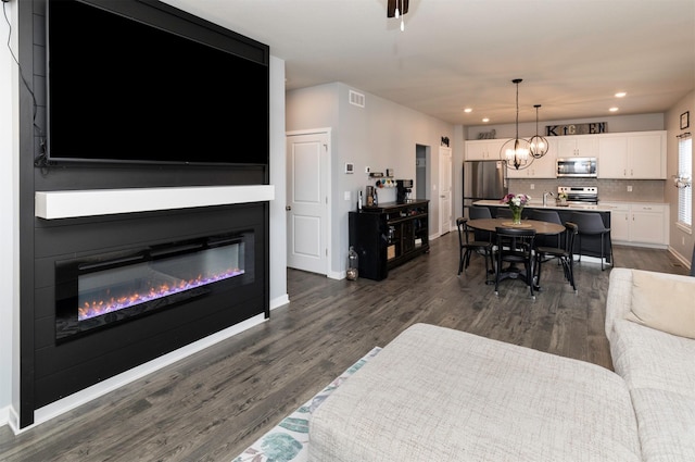 living room with an inviting chandelier and dark wood-type flooring