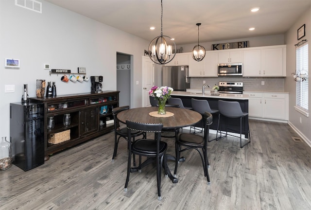 dining space featuring sink, an inviting chandelier, and light hardwood / wood-style flooring