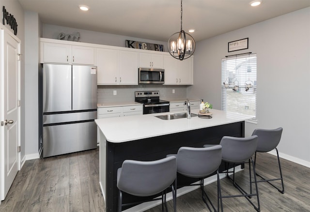 kitchen featuring appliances with stainless steel finishes, white cabinetry, sink, dark hardwood / wood-style flooring, and decorative backsplash