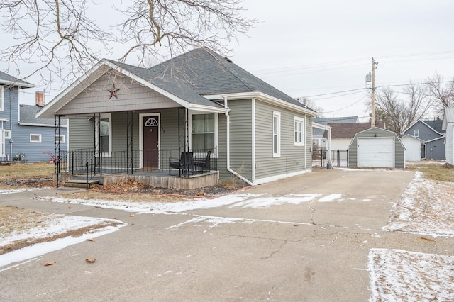 bungalow-style home with a porch, a garage, and an outdoor structure