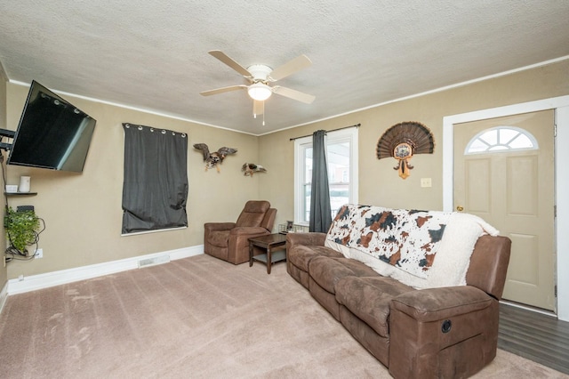 living room featuring ceiling fan, light colored carpet, and a textured ceiling