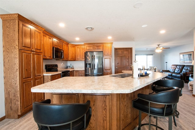 kitchen featuring a large island, light hardwood / wood-style floors, a breakfast bar, and appliances with stainless steel finishes