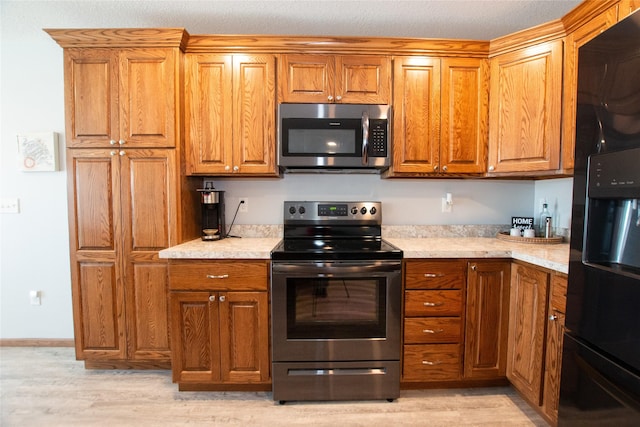 kitchen with appliances with stainless steel finishes and light hardwood / wood-style flooring