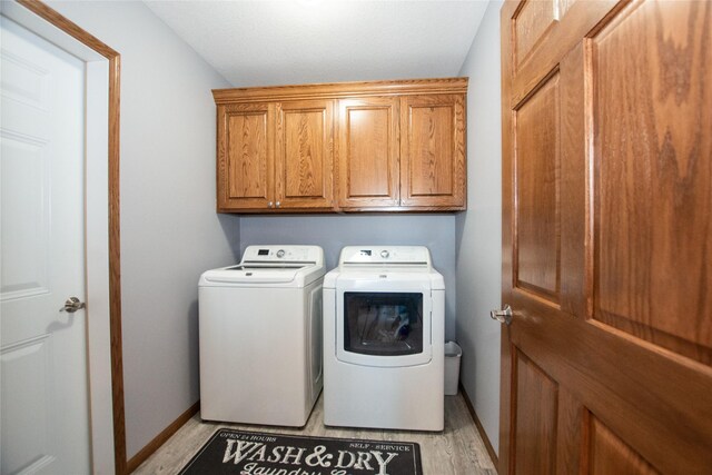 laundry area with cabinets, light hardwood / wood-style floors, and independent washer and dryer