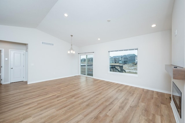 unfurnished living room featuring light hardwood / wood-style flooring, vaulted ceiling, and a chandelier