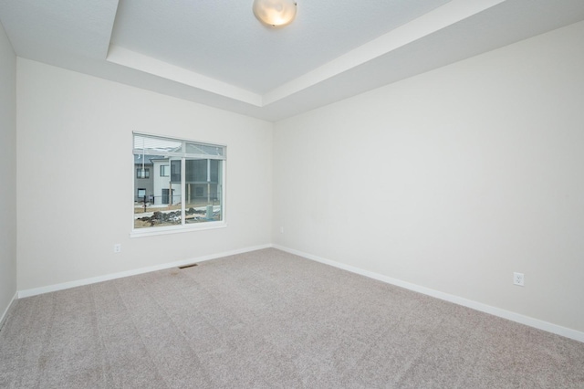 unfurnished room with carpet floors and a tray ceiling