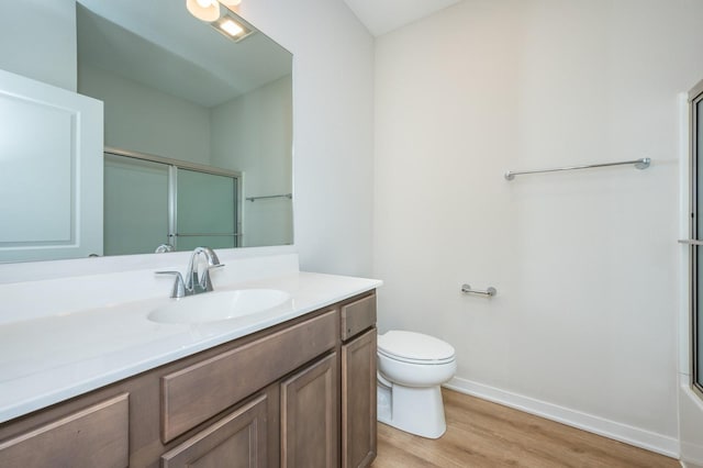 full bathroom with hardwood / wood-style flooring, vanity, bath / shower combo with glass door, and toilet