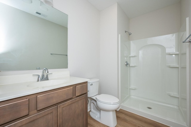 bathroom featuring walk in shower, vanity, toilet, and hardwood / wood-style floors