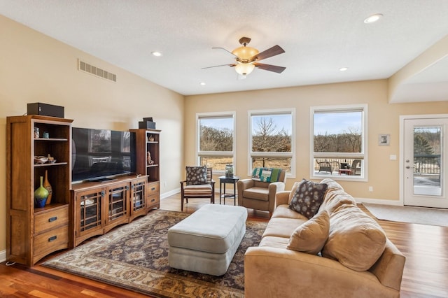 living room featuring ceiling fan, hardwood / wood-style floors, a textured ceiling, and a wealth of natural light