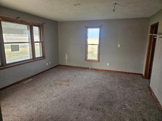 carpeted empty room featuring a textured ceiling