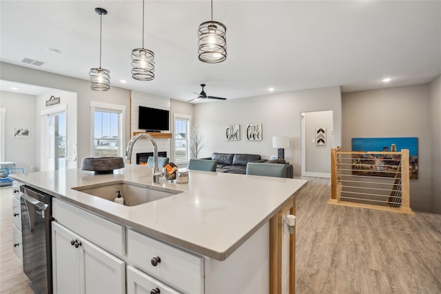 kitchen with sink, white cabinetry, a kitchen island with sink, black dishwasher, and decorative light fixtures