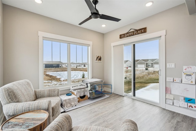 living area with wood-type flooring and ceiling fan