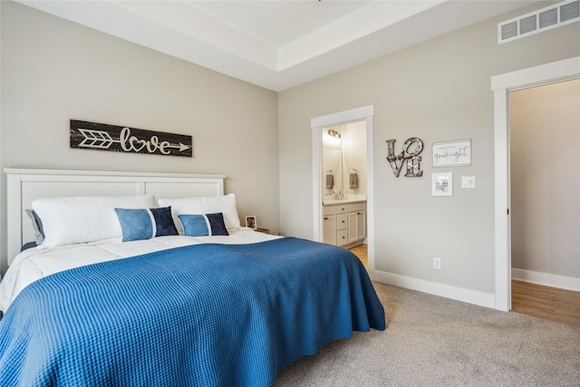 bedroom featuring light colored carpet and ensuite bathroom