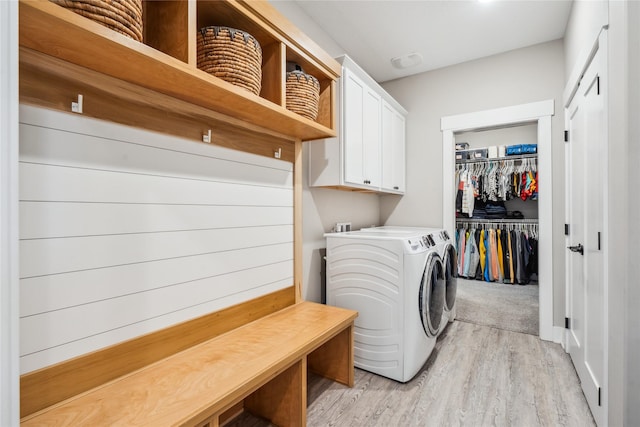 laundry room featuring independent washer and dryer, light hardwood / wood-style floors, and cabinets