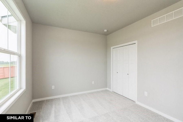 unfurnished bedroom with light colored carpet and a closet