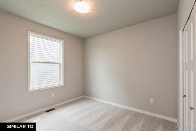 carpeted empty room with a textured ceiling