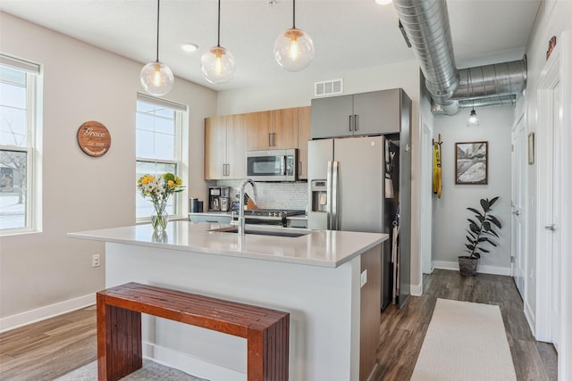 kitchen with sink, dark wood-type flooring, hanging light fixtures, and appliances with stainless steel finishes