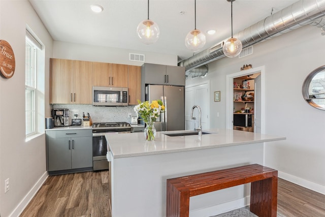 400 SW 7th St Unit 105, Des Moines, IA 50309 - kitchen with stainless steel appliances, dark wood finished floors, a sink, gray cabinetry, and tasteful backsplash