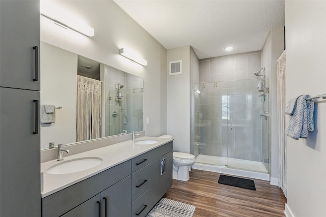 bathroom featuring toilet, a shower with shower door, a textured ceiling, vanity, and hardwood / wood-style floors