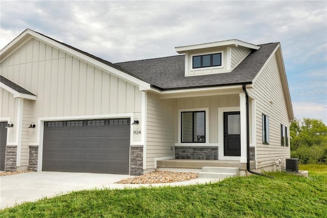 view of front of property with a garage, covered porch, cooling unit, and a front yard