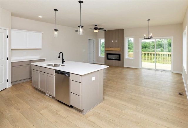 kitchen featuring sink, hanging light fixtures, light hardwood / wood-style floors, an island with sink, and stainless steel dishwasher