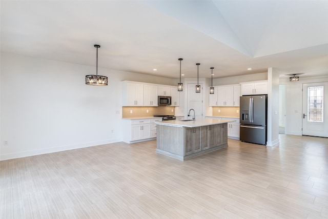 kitchen with white cabinetry, stainless steel appliances, a center island with sink, and pendant lighting