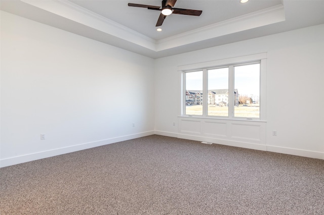 carpeted spare room featuring ceiling fan, ornamental molding, and a tray ceiling