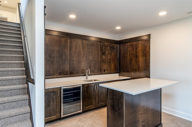 bar featuring dark brown cabinets, sink, and wine cooler