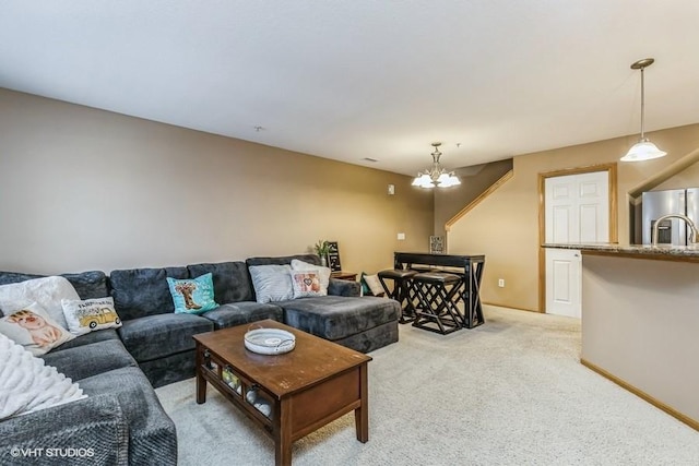 living room featuring an inviting chandelier, sink, and light carpet