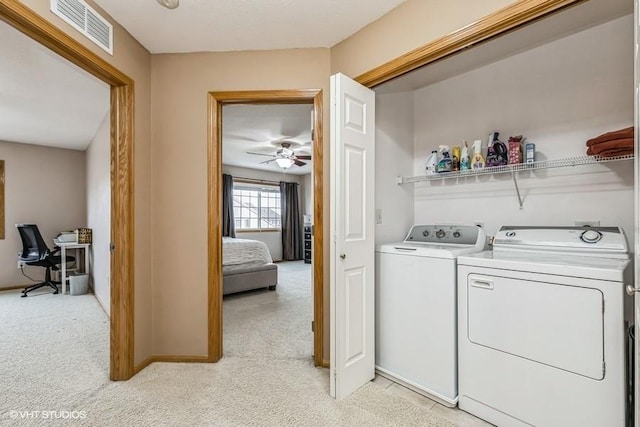 laundry room with light colored carpet, washing machine and dryer, and ceiling fan