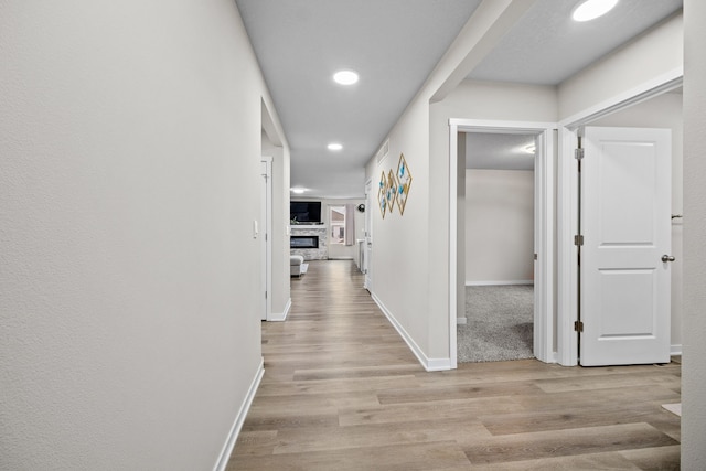 corridor with light wood-style flooring, baseboards, and recessed lighting