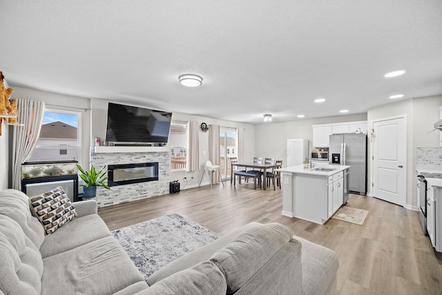 living room with sink, a fireplace, and light wood-type flooring