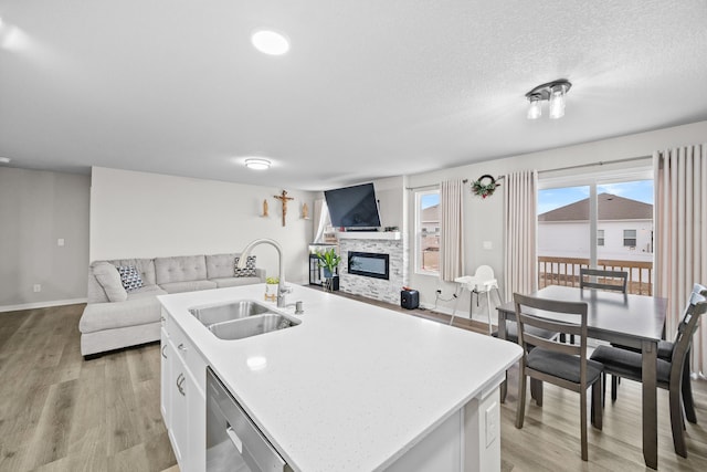 kitchen featuring a center island with sink, open floor plan, white cabinetry, a sink, and dishwasher