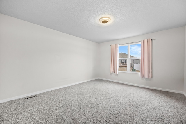 empty room with carpet floors and a textured ceiling