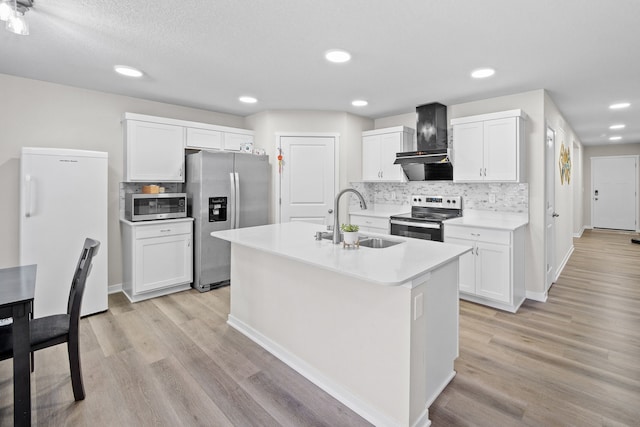 kitchen with wall chimney exhaust hood, sink, appliances with stainless steel finishes, a kitchen island with sink, and white cabinets