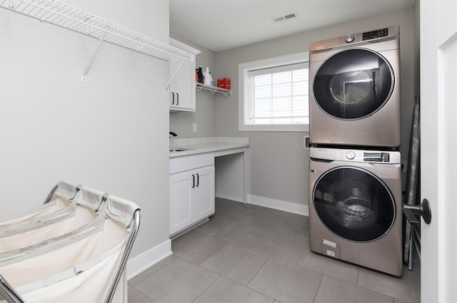 laundry area with cabinets and stacked washer / dryer