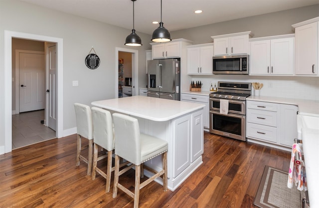 kitchen featuring a kitchen island, appliances with stainless steel finishes, white cabinets, backsplash, and hanging light fixtures