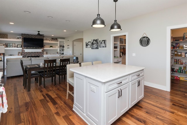 kitchen featuring a kitchen island, dark hardwood / wood-style floors, white cabinets, and decorative light fixtures