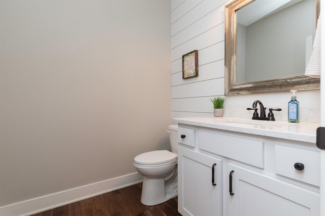 bathroom with vanity, wood-type flooring, wooden walls, and toilet