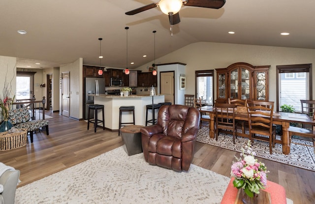 living room with lofted ceiling, a healthy amount of sunlight, dark wood-type flooring, and ceiling fan