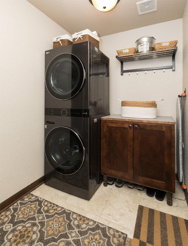 laundry room featuring cabinets and stacked washer / drying machine