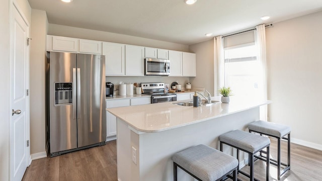 kitchen featuring a breakfast bar, sink, white cabinets, dark hardwood / wood-style flooring, and stainless steel appliances