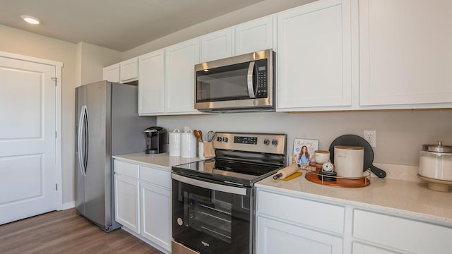 kitchen featuring stainless steel appliances, light stone countertops, dark wood-type flooring, and white cabinets