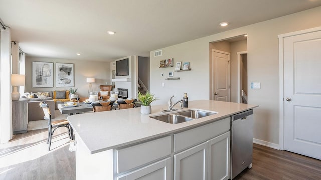 kitchen with sink, stainless steel dishwasher, a kitchen island with sink, and dark hardwood / wood-style floors