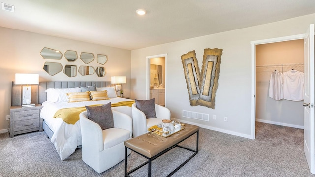 bedroom with light carpet, a walk in closet, a closet, and ensuite bathroom