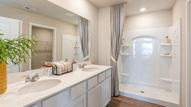 bathroom with a shower, hardwood / wood-style floors, and vanity