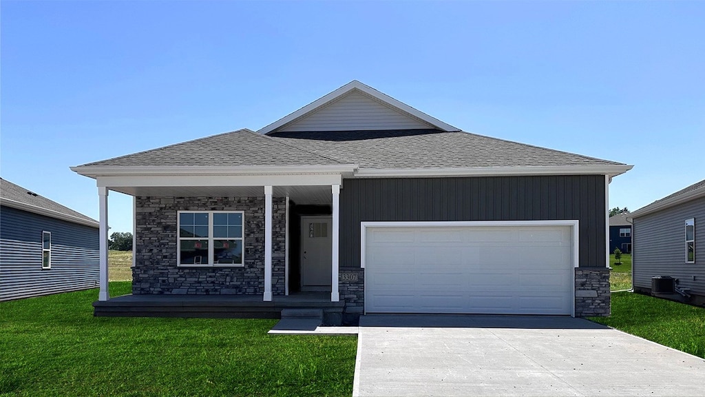 view of front of house with a porch, a garage, central AC unit, and a front lawn